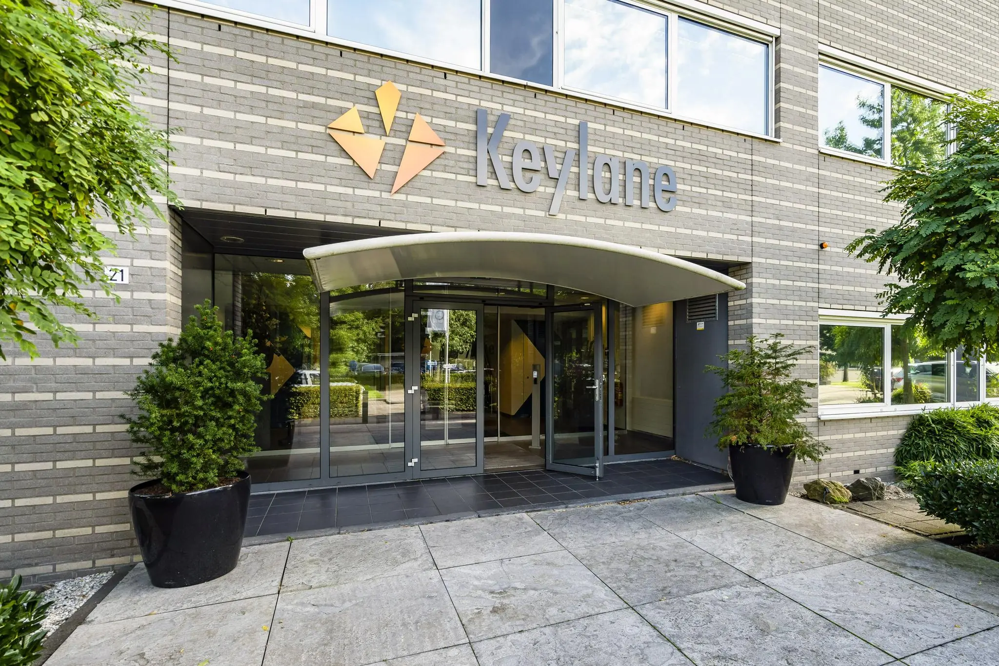 Ingang van het Keylane-kantoor aan de Jan Leentvaarlaan, met glazen deuren en bedrijfslogo op de gevel.